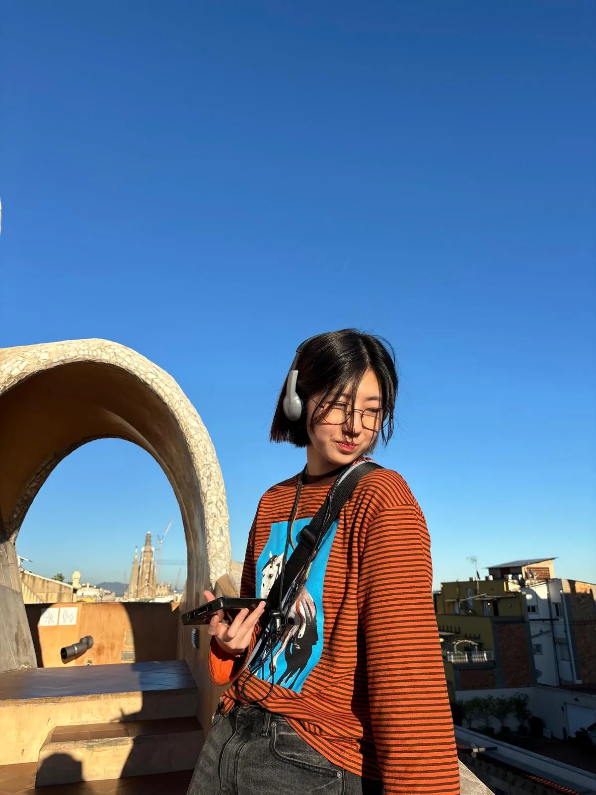 Rhea Park standing on a sunlit rooftop under a blue sky